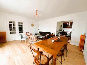 Un espacio habitable amplio con una gran mesa de madera, varias sillas, un sofá y una cocina al fondo.