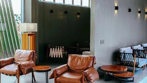 A modern lounge area with leather chairs, round tables, and a sofa.