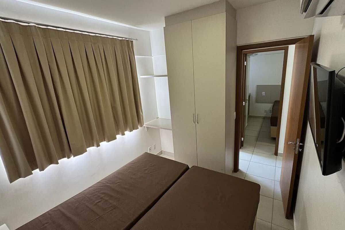 Una habitación con cama, armario y televisor.