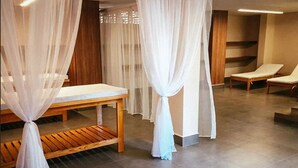 A spa room with a wooden bench, a massage table, and a white canopy.