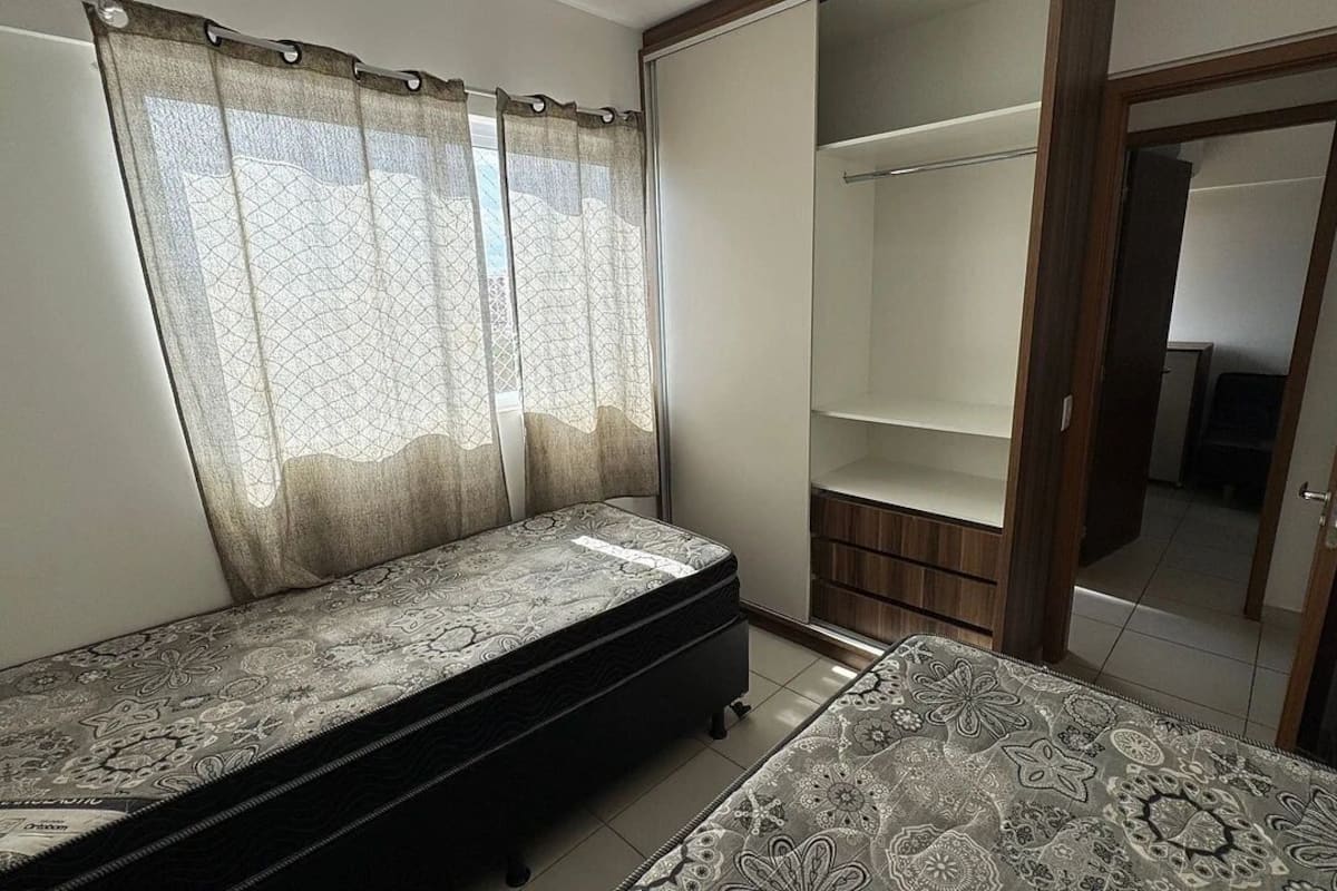 Un dormitorio con cama, armario y pequeño banco.