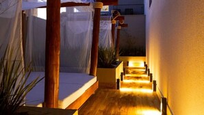 A wooden pathway leading to a covered area with a bench and plants.