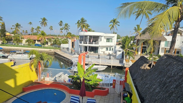 Un hôtel doté d’une piscine, offrant une vue sur le port de plaisance et bordé de palmiers.