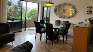 A spacious living area with a dining table, chairs, a sofa, a large mirror, and a view of the outdoors. - Charming, elegant cozy 1-bedroom condo in amazing Tijuana with AC main Blvd SAFE (Tijuana)