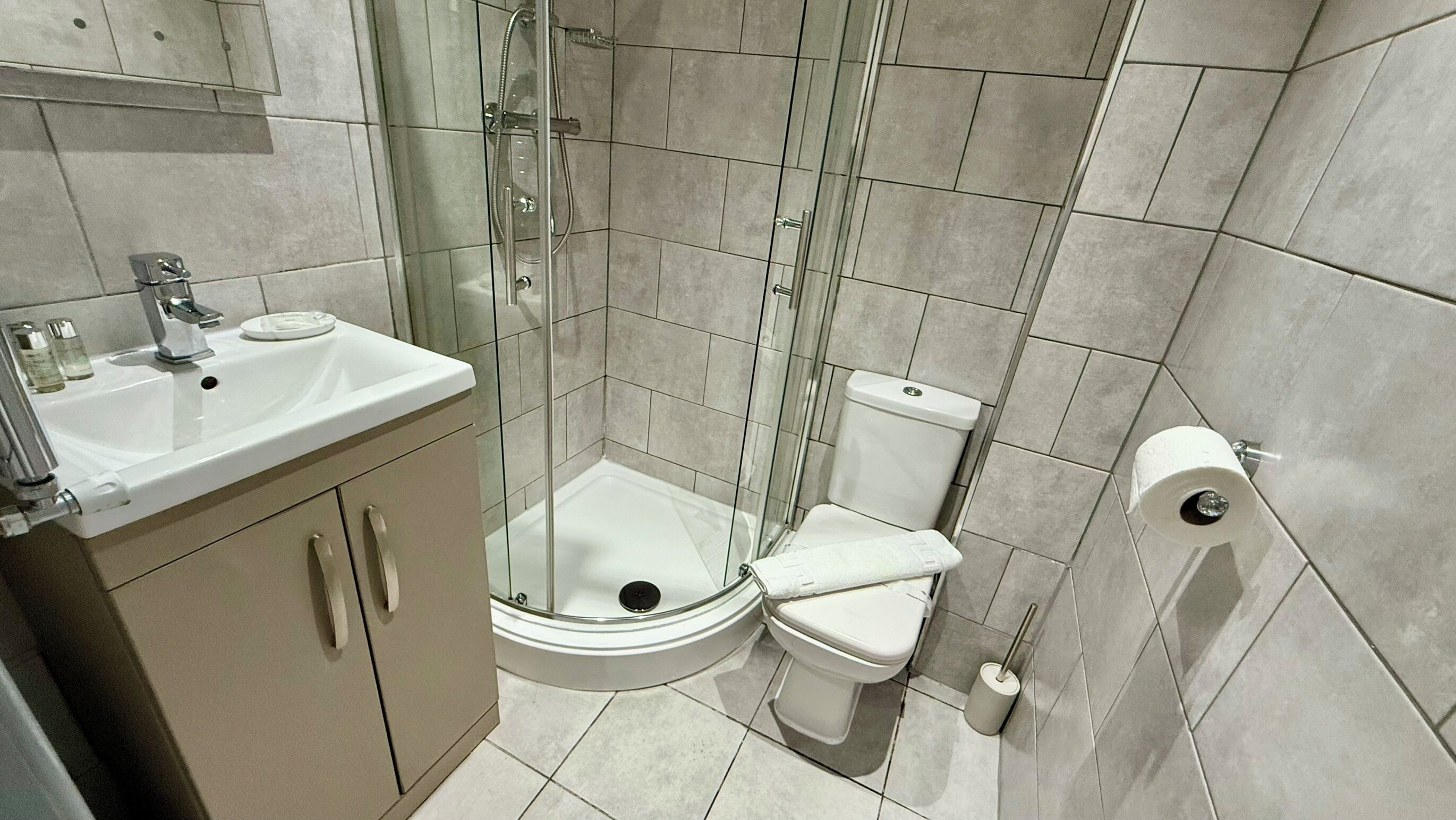 Un baño compacto con cabina de ducha de vidrio, un lavabo blanco y un inodoro.