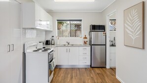Eine moderne Küche mit weißen Schränken, Edelstahlgeräten und Holzboden.