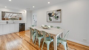 Una cocina moderna con armarios blancos, una mesa de comedor de madera y sillas verdes.
