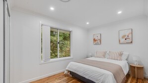 Un dormitorio con una cama, una ventana y dos cuadros colgados en la pared.