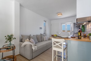 En moderne stue med sofa, spisebord og et køkken med komfur.