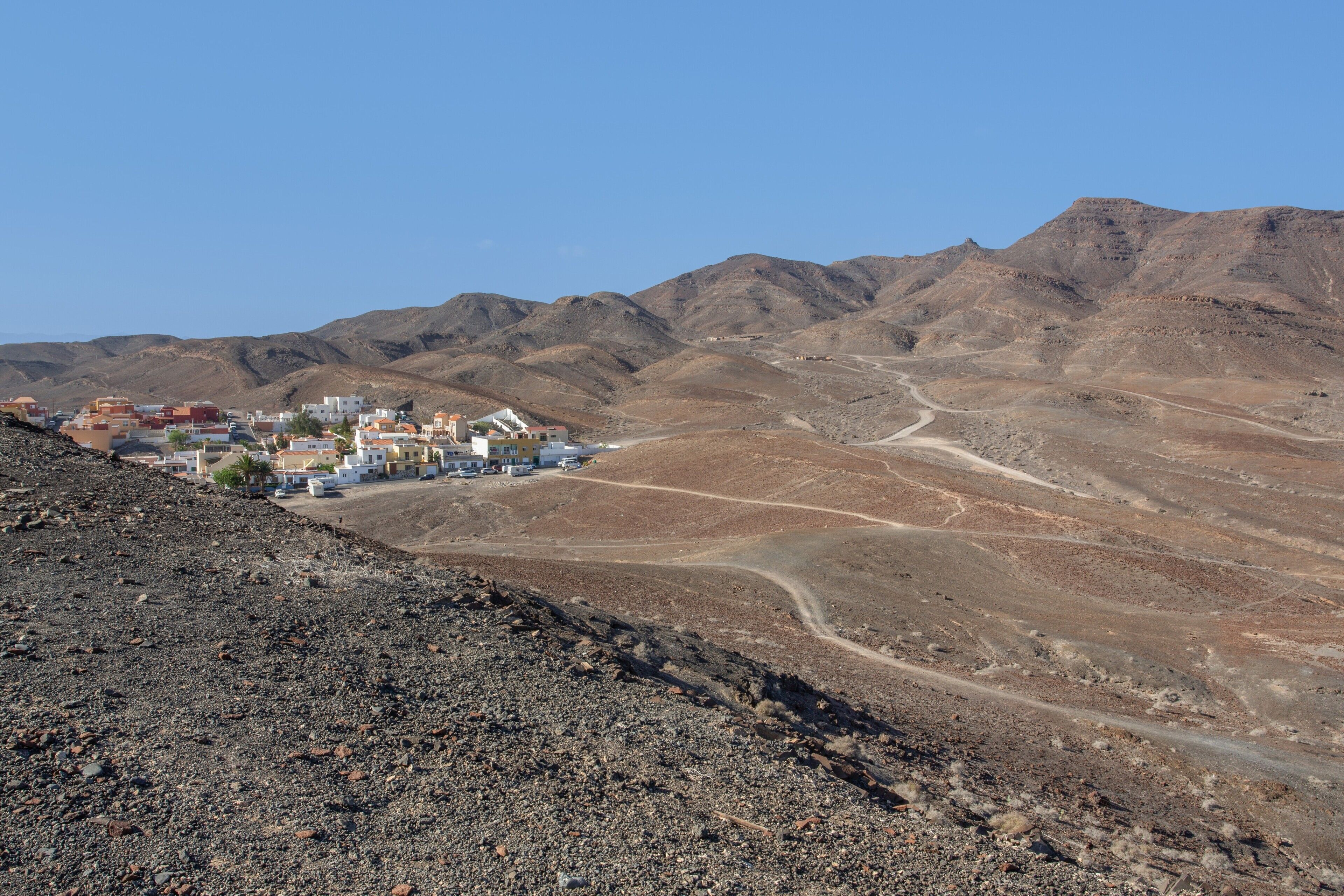 Paisaje desértico con un pequeño asentamiento y una carretera que lo atraviesa.