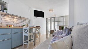 Una cocina moderna con zona de comedor, un televisor de pantalla plana y un sofá con cojines a rayas.