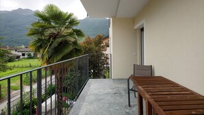 A balcony with a view of mountains, a palm tree, and a wooden table. - Apartment 'Appartamento' with Mountain View, Wi-Fi and Air Conditioning (San Cassiano)