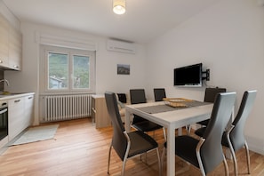 Una cocina moderna con comedor, televisor montado en la pared y ventana con vistas al exterior.