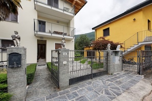 Un edificio de dos pisos con una puerta de entrada de piedra, un balcón y una escalera que lleva a un edificio amarillo.
