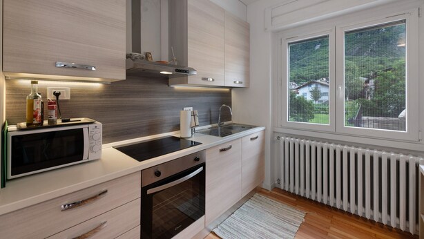 A modern kitchen with a microwave, oven, sink, and window overlooking greenery. - Apartment 'Appartamento' with Mountain View, Wi-Fi and Air Conditioning (San Cassiano)