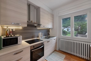 Cocina moderna con microondas, horno, lavamanos y ventana con vistas a zonas verdes.
