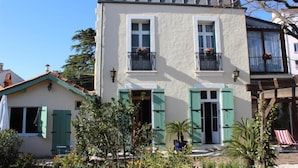 A two-story building with a balcony, shutters, and a small garden area. - Villa Kumquats (Béziers)