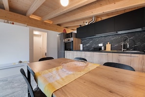 Una cocina moderna con vigas de madera, encimera de mármol y una mesa de comedor con un bol.
