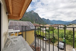 Un balcon avec vue sur les montagnes, une table avec des chaises et une voiture garée.