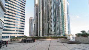A modern high-rise building with a courtyard featuring outdoor seating and a decorative fountain. - Magnificent 2BR at Dubai Marina (Dubai)