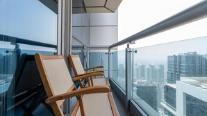 A balcony with two wooden chairs, a glass railing, and a city view. - Magnificent 2BR at Dubai Marina (Dubai)