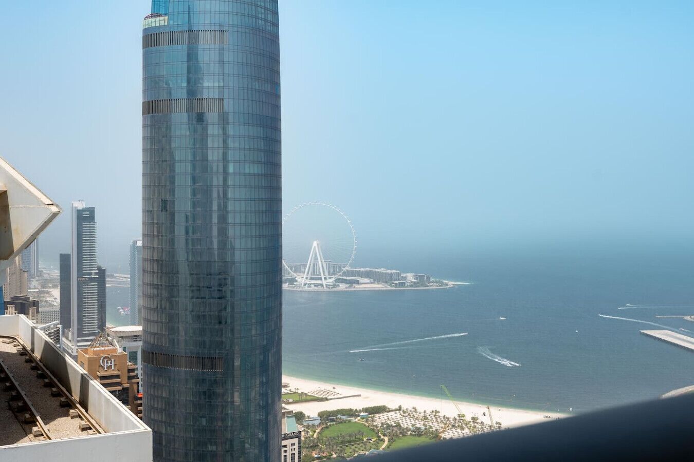 Un immeuble de grande hauteur offrant une vue sur une plage et une grande roue au loin.