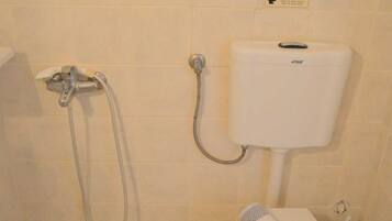 Et lille badeværelse med toilet, bruser og toiletpapirholder.