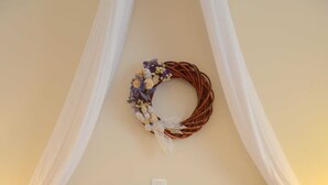 A neatly made bed with white linens and a floral wreath on the headboard.