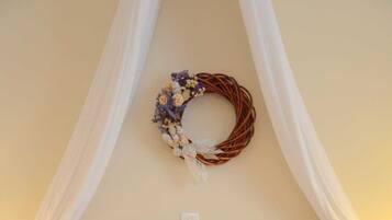 A neatly made bed with white linens and a floral wreath on the headboard.