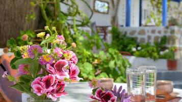 Dos frascos de vidrio con adornos de encaje y flores rosadas sobre una mesa al aire libre.