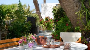 A table set outdoors with a rustic tablecloth, a wooden chair, and a variety of glass jars with flowers. - Gemilos Nook Rooms II -  Double bed, Apartment (Milos)