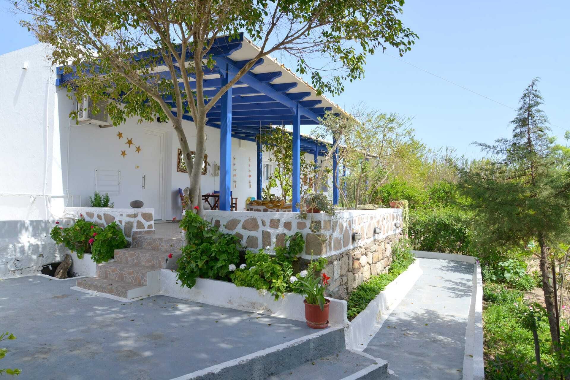 A white building with a blue roof and stone steps leading to a porch.