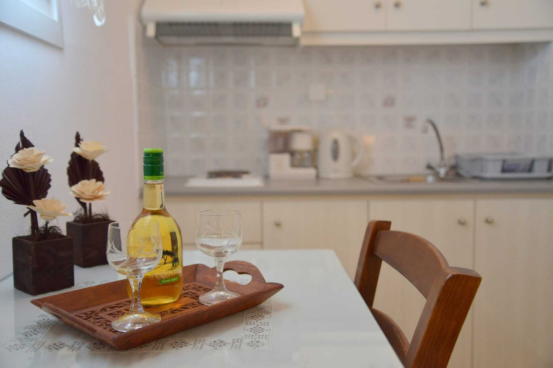 A dining table with a bottle of wine, two glasses, and decorative flowers.