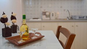 A dining table with a bottle of wine, two glasses, and decorative flowers. - Gemilos Nook Rooms II -  Double bed, Apartment (Milos)