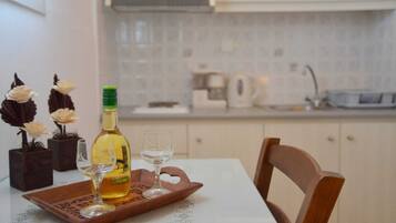 A dining table with a bottle of wine, two glasses, and decorative flowers.