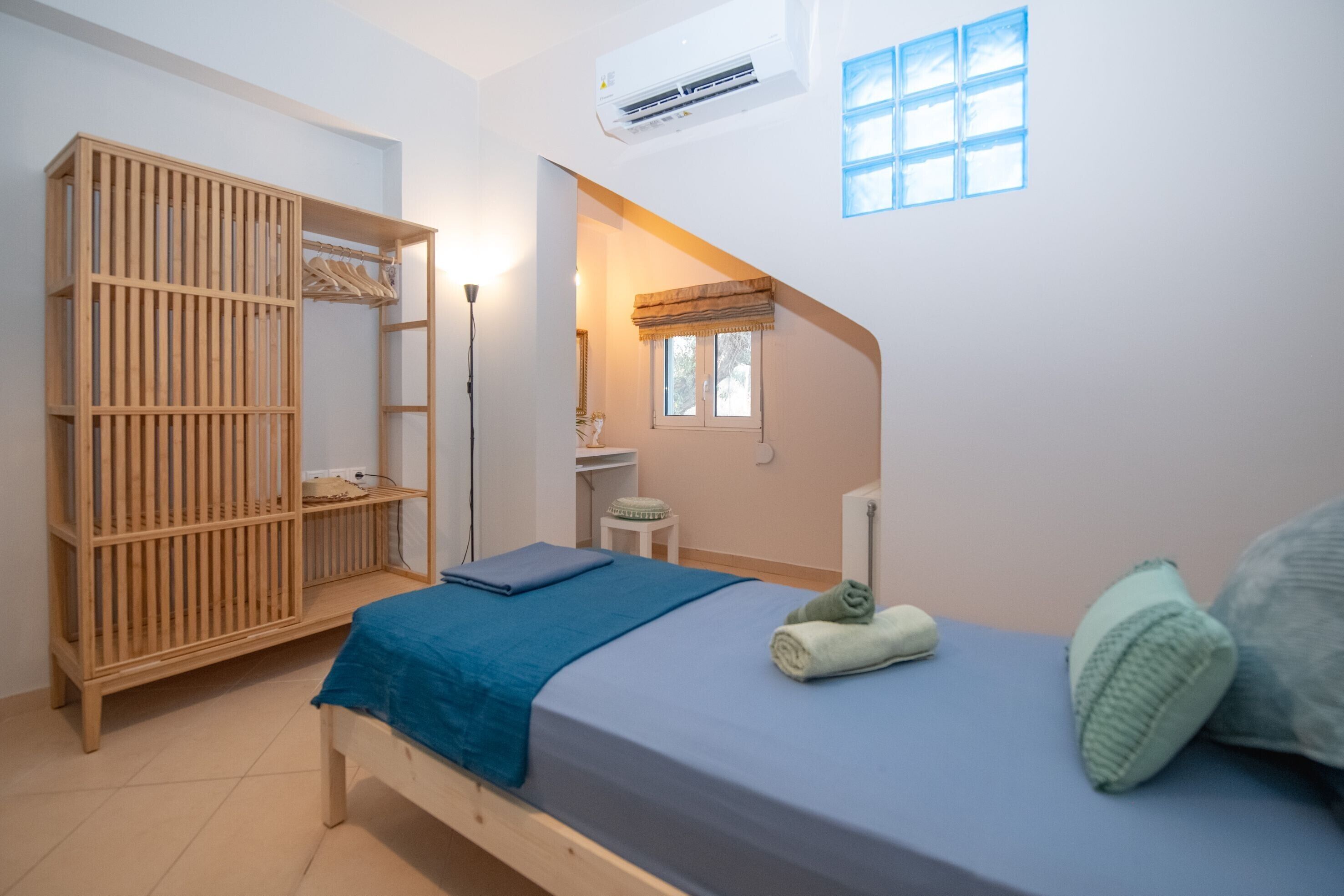 Une chambre à coucher comprenant un lit, une armoire, une fenêtre et un appareil de climatisation.