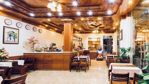 Un ristorante con soffitto e pareti in legno, un'area bar centrale e diversi tavoli e sedie.