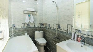 Un bagno con vasca, toilette e lavandino, pareti in marmo e uno specchio.