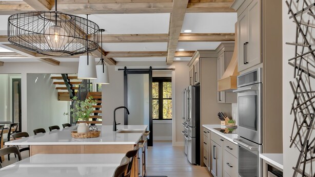 A modern kitchen with a central island, stainless steel appliances, and a large window.