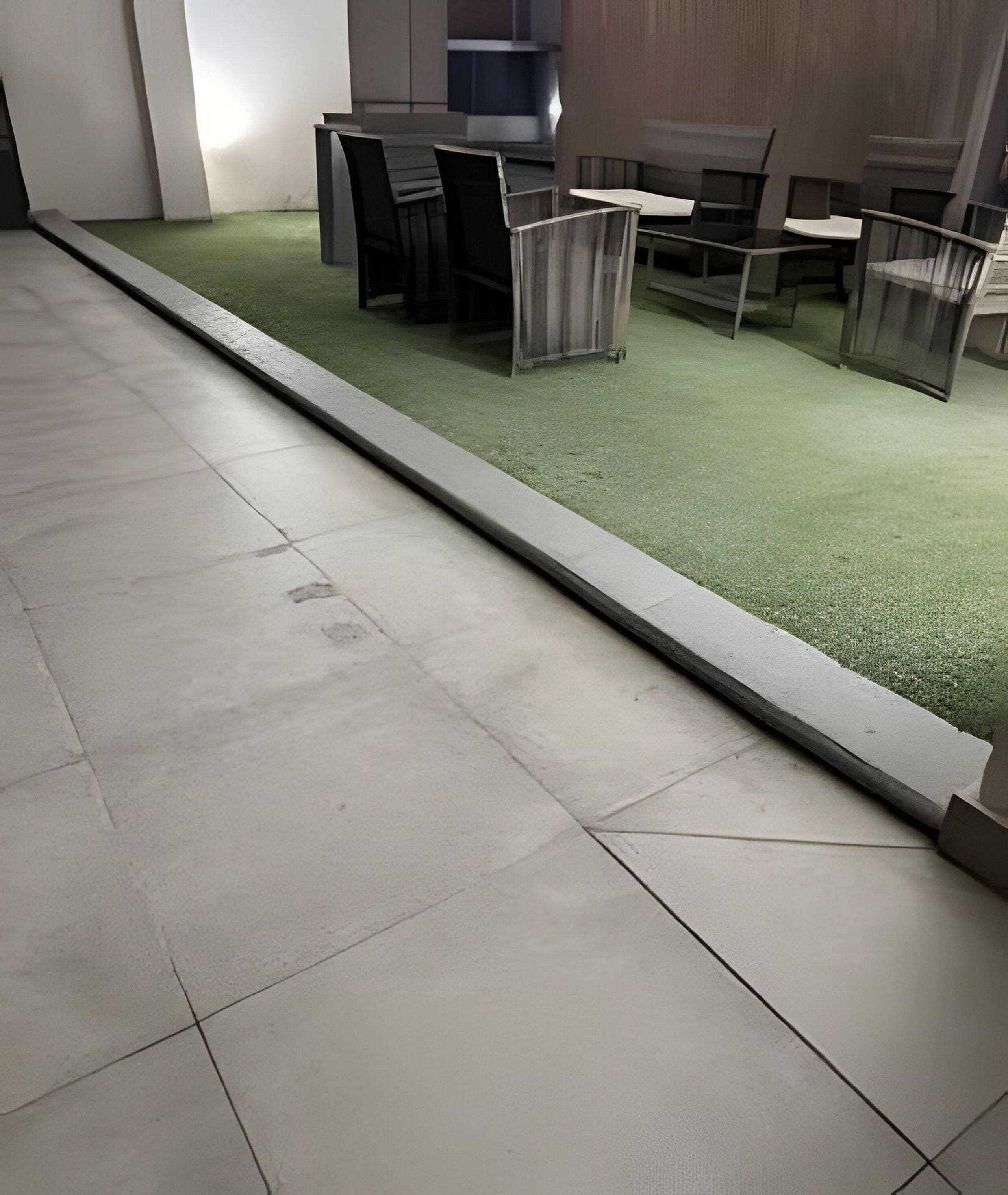 Un sol carrelé avec une zone recouverte d’une moquette verte, ainsi qu’une rangée de chaises et de tables.
