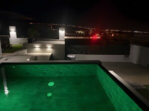 A swimming pool with steps leading up to it, surrounded by a modern outdoor area with a view of a cityscape at night. - Fuerteventura Velvet Golf Holiday Home with Private Pool, Wi-Fi & Air Conditioning (Antigua)