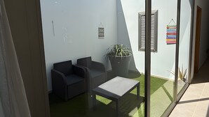 Ein moderner Sitzbereich im Freien mit einem Topfpflanzen, einem kleinen Tisch und einem an der Wand befestigten Schild.