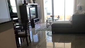 Un vaste espace de vie doté d’un plancher poli, d’un canapé, d’une table à manger avec des chaises et d’un meuble pour la télévision.