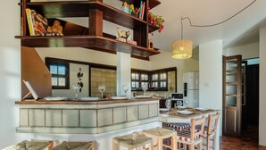A kitchen with a central island, bar stools, and a hanging light fixture.