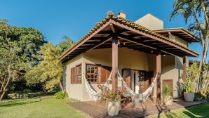 Une maison avec une véranda en bois, un hamac et des plantes en pot.