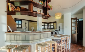 Een keuken met een centraal eiland, barstoelen en een hanglamp.