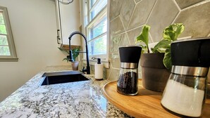 A kitchen with a granite countertop, a sink, a potted plant, a pepper grinder, and a salt shaker. - Meet Bev, a charming 2-bedroom, pet-friendly home in Rochester (Rochester)