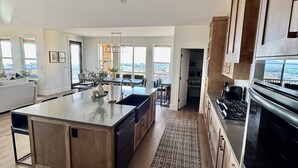 A spacious kitchen with a large island, wooden cabinets, and a view of the city. - Newly Built Gem with Panoramic Lake Views and Chic Interiors (Garden City)