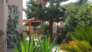 A garden with a pergola, various plants, and a stone wall. - Accommodation in Villa Cristina (Puglia)