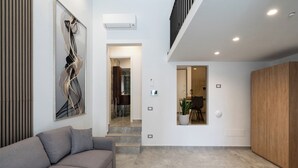 A modern living room with a grey sofa, a large abstract painting, and a wooden cabinet.